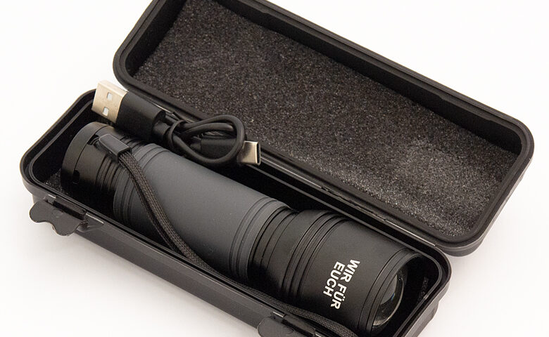 Schwarze Taschenlampe in einer schwarzen Kunststoffbox die mit Schaumstoff ausgepolstert ist auf weißem Hintergrund