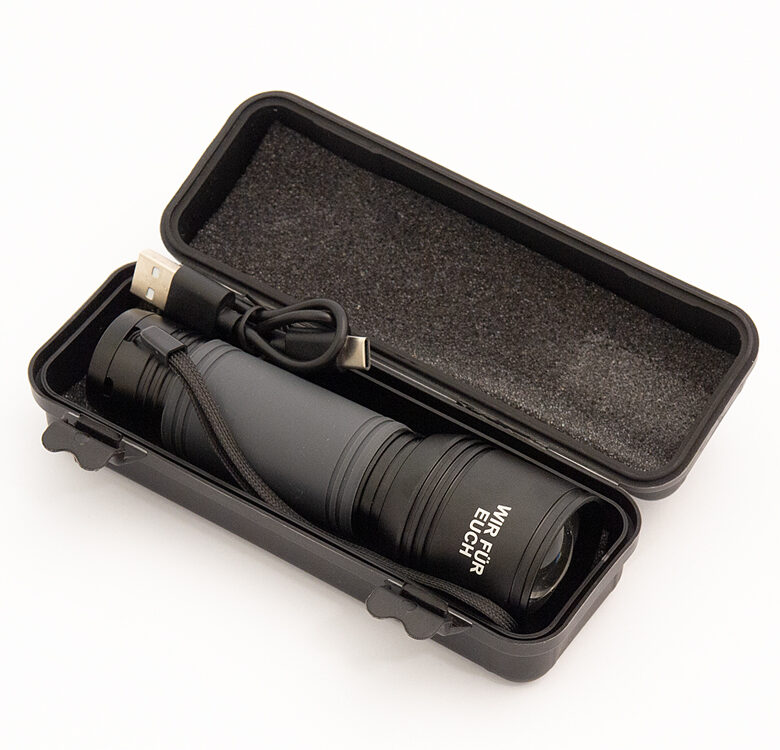 Schwarze Taschenlampe in einer schwarzen Kunststoffbox die mit Schaumstoff ausgepolstert ist auf weißem Hintergrund